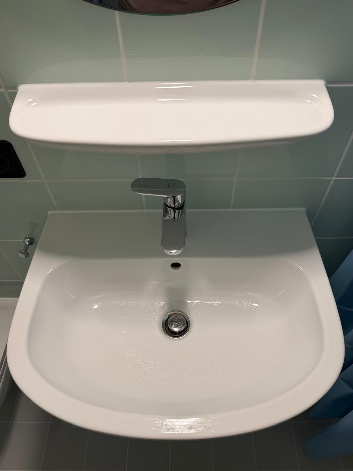 Détail d’un joint silicone blanc sous une tablette de lavabo