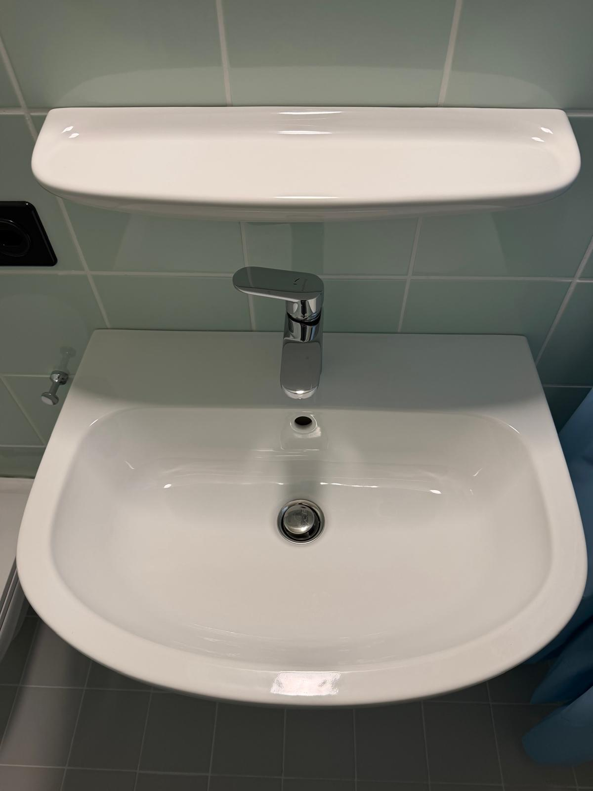 Joint silicone soigné entre le lavabo et le carrelage mural