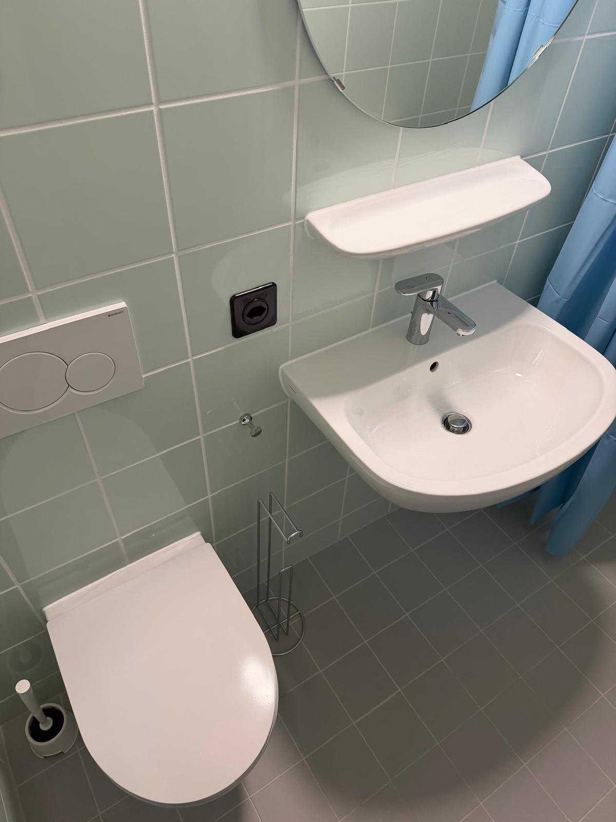 Finition des joints silicone dans une salle de bain carrelée vert d’eau